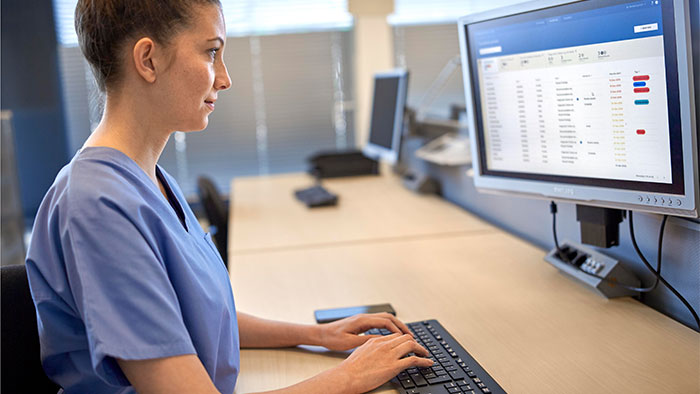 Medizinerin schaut auf einen Bildschirm und gibt &uuml;ber eine Tastatur Daten ein