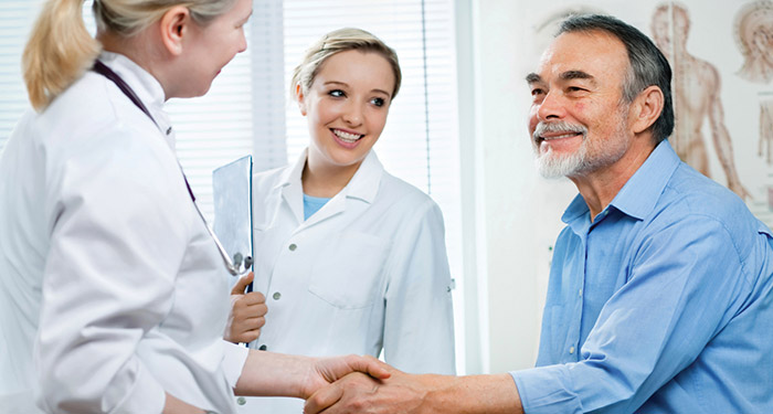 Zwei Mediziner, die einen Patienten begr&uuml;&szlig;en.