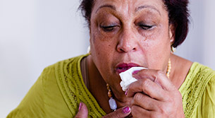 Unter einem Schub leidende Frau, die ein Taschentuch zum Gesicht f&uuml;hrt