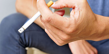 Hand, die eine angez&uuml;ndete Zigarette h&auml;lt