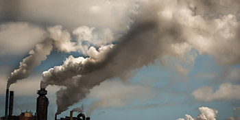 Skyline aus Fabrikschornsteinen mit Rauchschwaden, die die Luft verschmutzen
