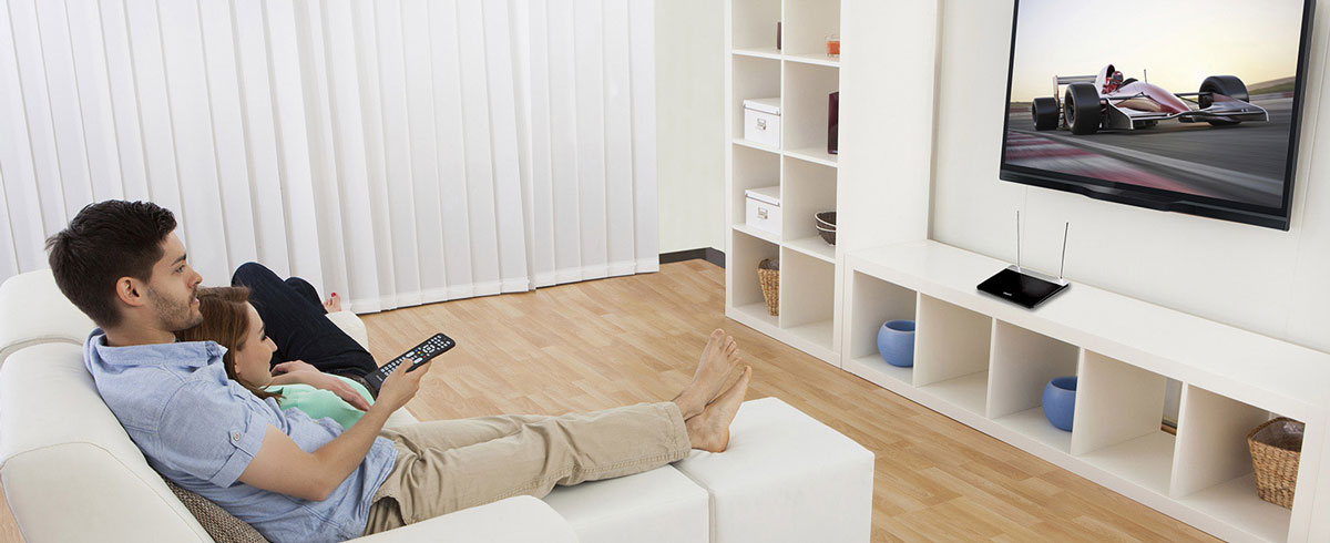 Ein Mann und eine Frau sitzen auf einem Sofa und schauen fern.