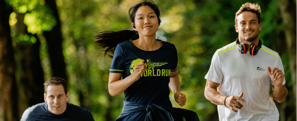 Drei Teilnehmer am Wings for Life World Run laufen mit einem Lachen auf dem Gesicht und tragen dabei Philips Sportkopfh&ouml;rer.
