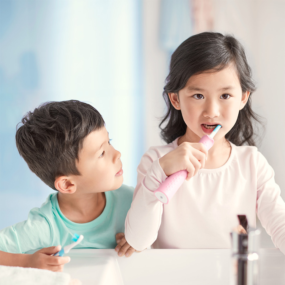 M&auml;dchen zeigt ihr L&auml;cheln und h&auml;lt eine Sonicare For Kids Schallzahnb&uuml;rste in der Hand