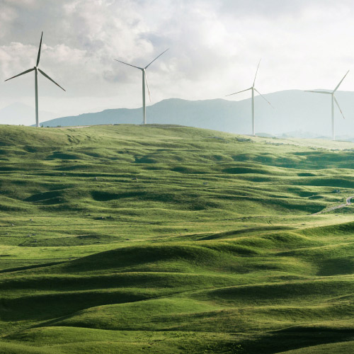 Ein Windpark mit gr&uuml;nen H&uuml;geln, der f&uuml;r saubere Energie und Nachhaltigkeit in Unternehmen steht